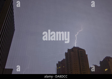 Blitze durchziehen den Himmel während eines Gewitters in der Nacht, gesehen über den beleuchteten Fenstern eines Wohnhauses im Chaoyang Bezirk von Peking, China. © Olli Geibel Stockfoto