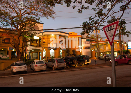 Ein Blick auf die Straße und Geschäfte und Autos in der Abenddämmerung in der Innenstadt von zentralen Playa Tamarindo, Guanacaste costarica Stockfoto