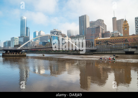 Ruderer auf den Yarra River und die Skyline der Innenstadt von Melbourne, Australien. Stockfoto