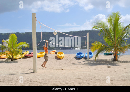 Leere Volleyballplatz auf Insel mit kleinen Jungen fangen Ball am Netz, Land und Meer im Hintergrund. Stockfoto