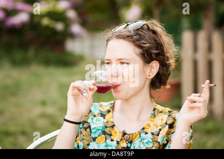 Schöne junge Frau Sangria trinken und Rauchen eine Zigarette auf einer Terrasse im freien Stockfoto