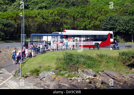 Island of Great Cumbrae, North Ayrshire, Schottland, Großbritannien, Montag, 8. Juli 2013. Passagiere in warmen Sonnenschein warten auf einen Bus in die Stadt Millport nach dem Segeln auf der Fähre von der Stadt Largs im Firth of Clyde Stockfoto