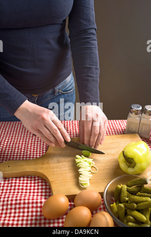 Weibliche Hände Lauch auf einer hölzernen Chopboard mit schwarzer Keramik Messer schneiden. Stockfoto