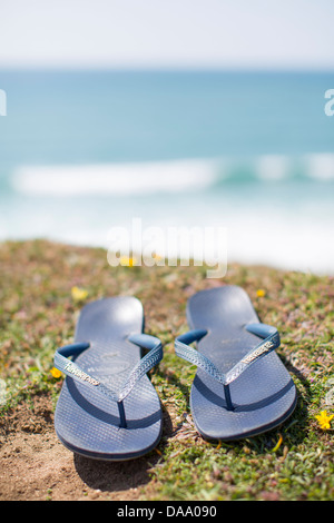 Ein paar Flip flop Sandalen auf einer Klippe über der Bucht von Sandymouth, Devon, England an einem sonnigen Sommertag. Stockfoto