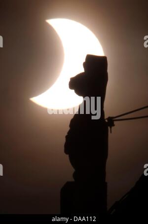 Die Sonne scheint hinter einer Skulptur sichelförmige während einer partiellen Sonnenfinsternis am Rathaus in Ilmenau, Deutschland, 4. Januar 2011. Das kosmische Schattenspiel kann in ganz Europa, sowie Teile von Afrika und Asien gesehen. Foto: Michael Reichel Stockfoto