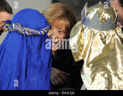 Bundeskanzlerin Angela Merkel eröffnet eine Kiste, die ihr vom Weihnachtslied des Bistums München-Freising in der Kanzlei in Berlin, Deutschland, 5. Januar 2011 gegeben wurde. Vier Gemeindediener jeweils aus 27 deutschen Diözesen vertreten die 500 000 Kinder, die an der 53. "Aktion Dreikoenigssingen" in Deutschland während der traditionelle Besuch der das Staatsoberhaupt in Berlin teilzunehmen. Foto: Raine Stockfoto