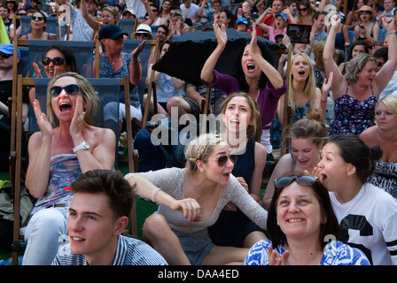 Menschen, die Tennis-Emotionen sehen, treffen glückliche Sportfans Teenager Mädchen junge Erwachsene, die Live-Sport auf dem riesigen Fernsehbildschirm beobachten. Wimbledon Town Centre London England 2013 2010s HOMER SYKES ist glücklich über die Art und Weise, wie das Spiel läuft Stockfoto