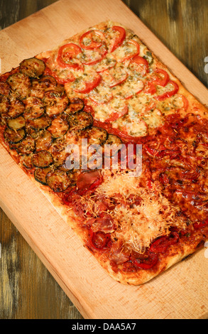 Quadratische hausgemachte Pizza vier Geschmacksrichtungen auf Holzbrett Stockfoto