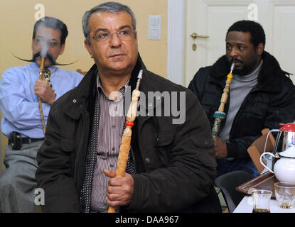 Tunesians Lassaad Dahmani (L-R), Boudaya Abdessatar Und Hedi Sdira sehen Sie die aktuelle News berichtet aus ihrem Heimatland an der tunesischen Gesellschaft "El Kantara" in Berlin, Deutschland, 15. Januar 2011 unterstützen. Bürgerinnen und Bürger treffen sich regelmäßig in den letzten Tagen, um aktuelle Entwicklungen in Tunesien und informieren Sie sich in den Räumen des Vereins. Foto: Britta Pedersen Stockfoto