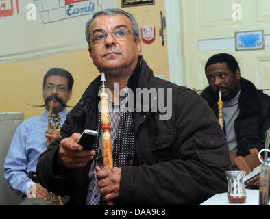 Tunesians Lassaad Dahmani (L-R), Boudaya Abdessatar Und Hedi Sdira sehen Sie die aktuelle News berichtet aus ihrem Heimatland an der tunesischen Gesellschaft "El Kantara" in Berlin, Deutschland, 15. Januar 2011 unterstützen. Bürgerinnen und Bürger treffen sich regelmäßig in den letzten Tagen, um aktuelle Entwicklungen in Tunesien und informieren Sie sich in den Räumen des Vereins. Foto: Britta Pedersen Stockfoto