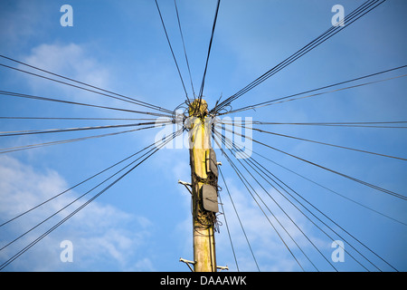 Telefonleitungen, die strahlenförmig von der Telegraph Pole gegen blauen Himmel Stockfoto