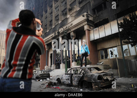 Zuschauer besuchen die geplündert und ausgebrannt an der "Nationaldemokratischen Partei", die regierende Partei von Ägyptens Präsident Hosni Mubarak, in Kairo, Ägypten, 29. Januar 2011 Hauptsitz. Weit verbreitet, Plünderungen und Ausschreitungen haben an diesem Samstag in Ägyptens Hauptstadt weiter. Die Augenzeugenberichte erzählte der Plünderung der Geschäfte geht, während in zwei Bezirken von Kairo, Polizeistationen gestürmt wurden Stockfoto