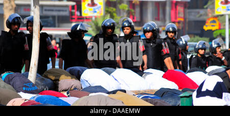 Bereitschaftspolizei haben hinter Menschen beten in Kairo, Ägypten, 28. Januar 2011 aufgereiht. Nach der Jumu'ah (Freitagsgebet) brach das ägyptische Volk Unzufriedenheit. Hunderttausende auf die Straße gegangen, bis das Militär bei Einbruch der Dunkelheit zog. Foto: Matthias Toedt Stockfoto