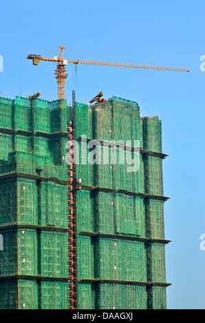 Ein Kran sitzt auf Bambus-Gerüst, die eine Neuentwicklung von Wohneigentum in dieser Taipa Baustelle umgibt. Stockfoto