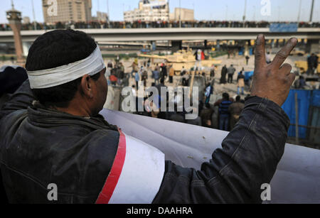 Ein Mann mit einem Verband um den Kopf liegt bei einer Zufahrtsstraße zum Tahrir-Platz in Kairo, Ägypten, 3. Februar 2011. Befürworter des Präsidenten befinden sich auf einer Brücke gegenüber ihm. Bei Konflikten zwischen den Befürwortern und Gegnern des Mubarak wurden bereits mehr als 800 Menschen verletzt. Foto: HANNIBAL Stockfoto