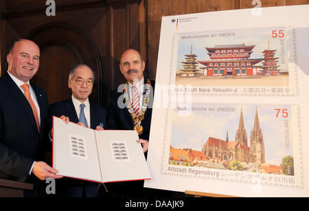 Der Paliamentary Staatssekretär des Bundesministeriums der Finanzen, Harmut Koschyk (CSU, L-R) der japanische Botschafter in Deutschland, Takahiro Shinyo und der Bürgermeister von Regensburg, Hans Schaidinger, stehen neben ein vergrößertes Bild von einer Briefmarke, die Darstellung der Regensburger Dom (siehe unten) und der Yakushi-Ji-Tempel in Nara, Japan in Regensburg, Deutschland, 4. Februar 2011.  Die 75 cent Stockfoto