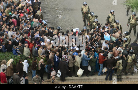 Demonstranten versammeln sich hinter einem Checkpoint, wo ägyptische Soldaten suchen, bevor sie auf dem Tahrir-Platz in Kairo, Ägypten, 6. Februar 2011 dürfen. Proteste gegen die Regierung trat ihre 13. Tag in Ägypten als Lösungen gesucht wurden, um eine Machtverschiebung herbeizuführen, um politischen Lähmung des Landes zu beenden.  Foto: HANNIBAL HANSCHKE Stockfoto
