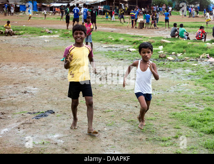 Mumbai-Fischer und ihre Kinder spielen Cricket während der Monsun-Wetter sie hält Angeln auf Brachland hinter Slums. Stockfoto