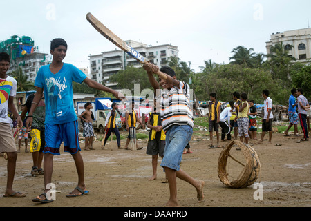 Mumbai-Fischer und ihre Kinder spielen Cricket während der Monsun-Wetter sie hält Angeln auf Brachland hinter Slums. Stockfoto