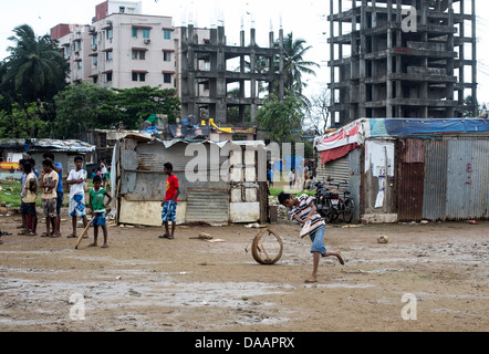 Mumbai-Fischer und ihre Kinder spielen Cricket während der Monsun-Wetter sie hält Angeln auf Brachland hinter Slums. Stockfoto