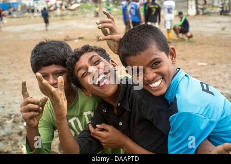 Mumbai-Fischer und ihre Kinder spielen Cricket während der Monsun-Wetter sie hält Angeln auf Brachland hinter Slums. Stockfoto