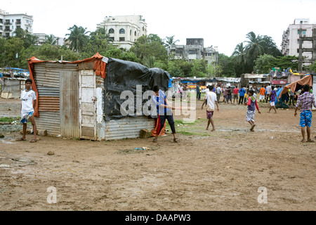 Mumbai-Fischer und ihre Kinder spielen Cricket während der Monsun-Wetter sie hält Angeln auf Brachland hinter Slums. Stockfoto