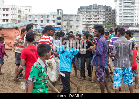 Mumbai-Fischer und ihre Kinder spielen Cricket während der Monsun-Wetter sie hält Angeln auf Brachland hinter Slums. Stockfoto