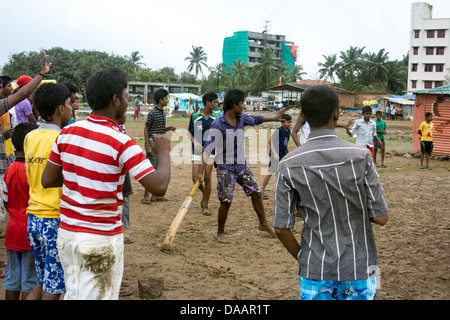 Mumbai-Fischer und ihre Kinder spielen Cricket während der Monsun-Wetter sie hält Angeln auf Brachland hinter Slums. Stockfoto