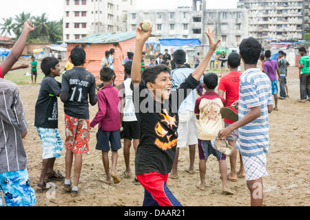 Mumbai-Fischer und ihre Kinder spielen Cricket während der Monsun-Wetter sie hält Angeln auf Brachland hinter Slums. Stockfoto