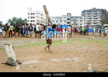 Mumbai-Fischer und ihre Kinder spielen Cricket während der Monsun-Wetter sie hält Angeln auf Brachland hinter Slums. Stockfoto