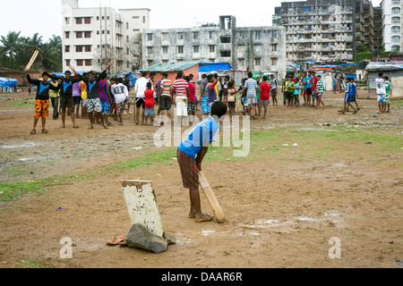 Mumbai-Fischer und ihre Kinder spielen Cricket während der Monsun-Wetter sie hält Angeln auf Brachland hinter Slums. Stockfoto