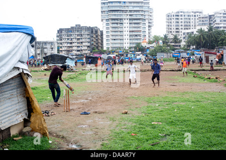 Mumbai-Fischer und ihre Kinder spielen Cricket während der Monsun-Wetter sie hält Angeln auf Brachland hinter Slums. Stockfoto