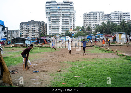 Mumbai-Fischer und ihre Kinder spielen Cricket während der Monsun-Wetter sie hält Angeln auf Brachland hinter Slums. Stockfoto