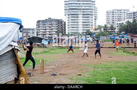 Mumbai-Fischer und ihre Kinder spielen Cricket während der Monsun-Wetter sie hält Angeln auf Brachland hinter Slums. Stockfoto