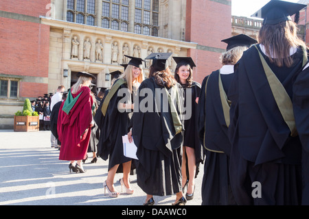 Absolventinnen und Absolventen nach einer Abschlussfeier an der Universität Birmingham, UK zusammenstehen. Stockfoto