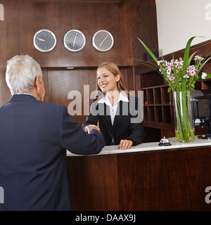 Lächelnde Angestellte an der Rezeption im Hotel geben Händedruck senior Gast Stockfoto