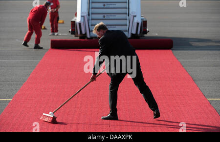 Ein Mann reinigt den roten Teppich vor der Ankunft von Papst Benedict XVI am Flughafen Tegel in Berlin, 22. September 2011. Der Leiter der römisch-katholischen Kirche besucht Deutschland vom 22-25 September 2011. Foto: Maurizio Gambarini Stockfoto