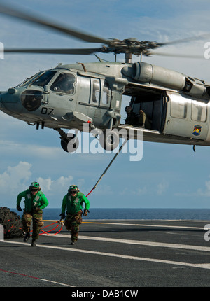 Logistikspezialist 3. Klasse Adrian Landa, links, und Flieger Robert Tindell Lauf zur Deckung nach der Befestigung der Ladung Beine, einen MH-60 Seahawk-Hubschrauber von der Insel Ritter der Hubschrauber Meer bekämpfen Squadron (HSC) 25 an Bord des Flugzeugträgers USS George Stockfoto