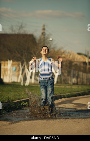 wenig glücklich junge Stand in Pfütze Stockfoto