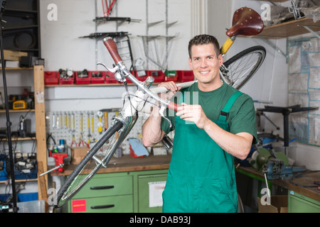 Zweiradmechaniker tragen eine Fahrrad in Werkstatt lächelnd in die Kamera Stockfoto