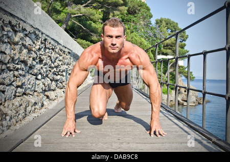 Jung, gut aussehend Bodybuilder bereit zu sprinten und laufen im freien Stockfoto
