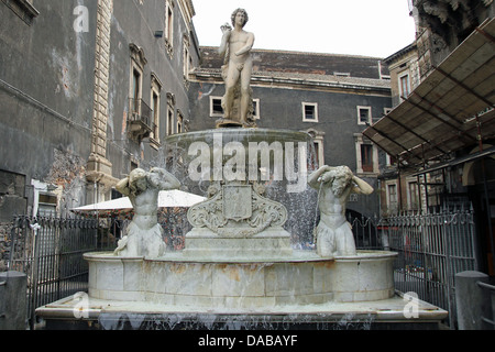 Der Amenano-Brunnen (Fontana dell'Amenano), erbaut im Jahre 1867 von Meister neapolitanischen Tito Angelini aus Carrara-Marmor, stellvertretend für den Fluss Amenano als junger Mann hält ein Füllhorn aus denen fließt das Wasser, die gegossen wird in einen Tank vom Rand konvex. Das Wasser aus diesem Tank überläuft produziert eine Effekt-Kaskade, die das Gefühl eines Blattes gibt. Daher das Sprichwort im sizilianischen "Wasser Linzolu' um den Brunnen anzugeben. Das Wasser, das aus dem Tank fällt gießt in den Fluss unten fließt auf einem Niveau von etwa zwei Meter unterhalb des Quadrats. Stockfoto