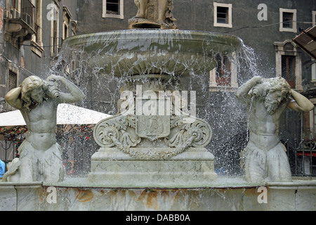 Der Amenano-Brunnen (Fontana dell'Amenano), erbaut im Jahre 1867 von Meister neapolitanischen Tito Angelini aus Carrara-Marmor, stellvertretend für den Fluss Amenano als junger Mann hält ein Füllhorn aus denen fließt das Wasser, die gegossen wird in einen Tank vom Rand konvex. Das Wasser aus diesem Tank überläuft produziert eine Effekt-Kaskade, die das Gefühl eines Blattes gibt. Daher das Sprichwort im sizilianischen "Wasser Linzolu' um den Brunnen anzugeben. Das Wasser, das aus dem Tank fällt gießt in den Fluss unten fließt auf einem Niveau von etwa zwei Meter unterhalb des Quadrats. Stockfoto