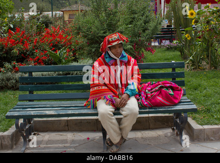 Porträt einer Peruanischen Mann in farbenfrohen traditionellen Poncho und Hut gekleidet, sitzen auf einer Parkbank, Ollantaytambo, das Heilige Tal, Peru. Stockfoto