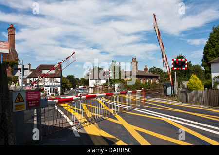 Barrieren fallen bei einem englischen Bahnübergang wie im New Forest, ein Zug nähert. Brockenhurst, Hampshire, England, GB, UK Stockfoto