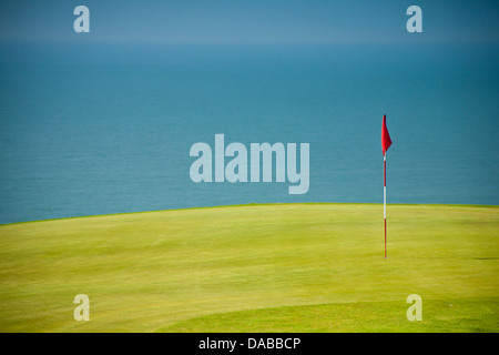 Golfflagge in hellem Grün Grün mit Blau des Meeres im Hintergrund. Stockfoto