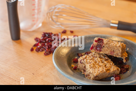 Frische hausgemachte gesunde Müsliriegel auf einem Keramik Teller bereit, gegessen zu werden. Mit leckeren Cranberries und Haferflocken gebacken. Stockfoto