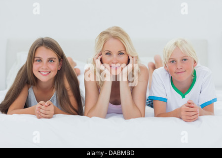 Geschwister und Mutter am Bett liegen Stockfoto