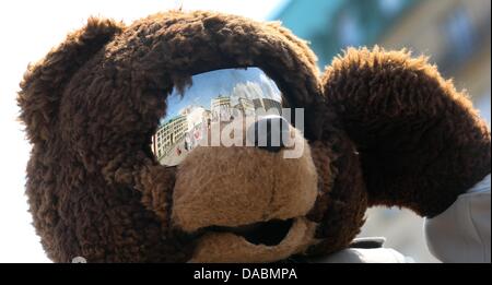 Das Brandenburger Tor und Pariser Platz spiegeln sich in der gespiegelten Maske der Straßenkünstler in einem Berliner Bär Kostüm in Berlin, Deutschland, 10. Juli 2013. Foto: KAY NIETFELD Stockfoto