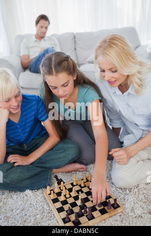 Geschwister und Mutter sitzt auf einem Teppich Schach spielen Stockfoto